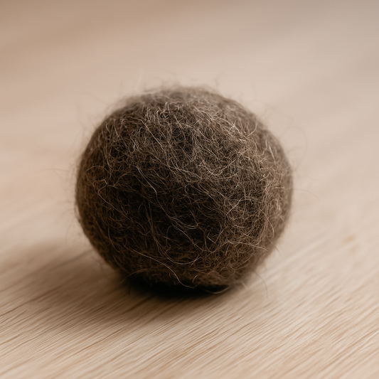 Bola de pelo de un gato color café, sobre un fondo de madera.